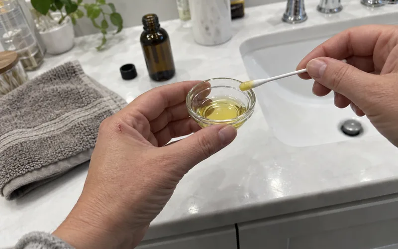 Hand holding a cotton swab dipped in diluted oregano oil blend