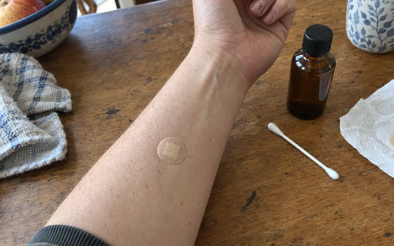 Small bandage on an inner forearm covering an oregano oil patch test