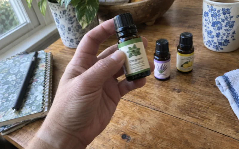 Hand holding a bottle of oregano essential oil to check the label